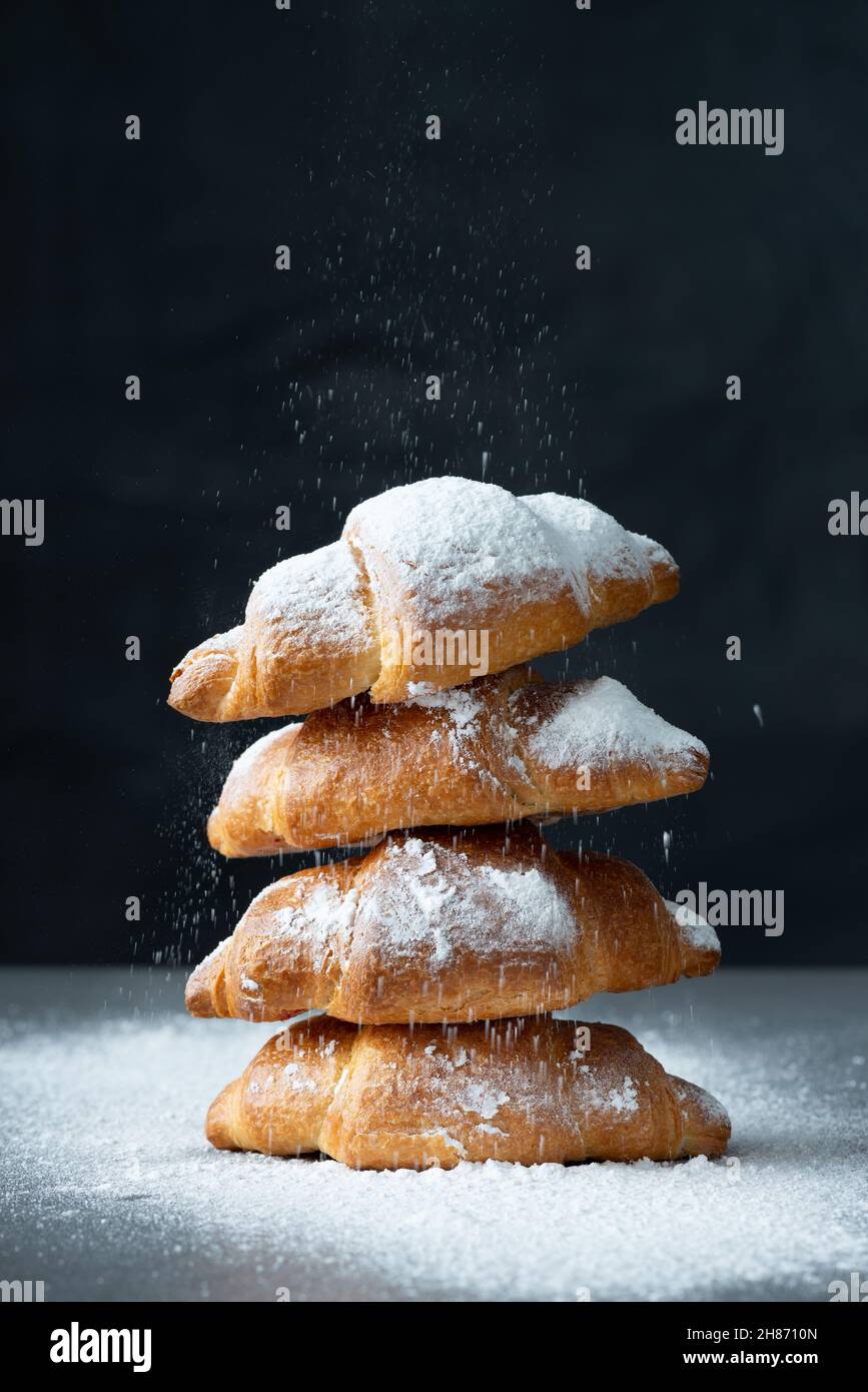 Close up of pile of croissants on a dark background. Sugar glass falling.  Stock Photo