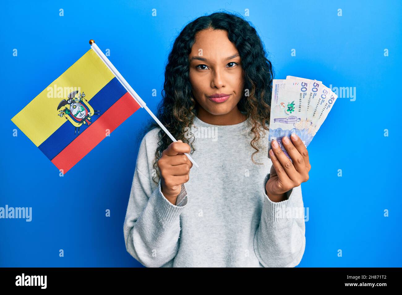 Young latin woman holding colombia flag and colombian pesos banknotes ...
