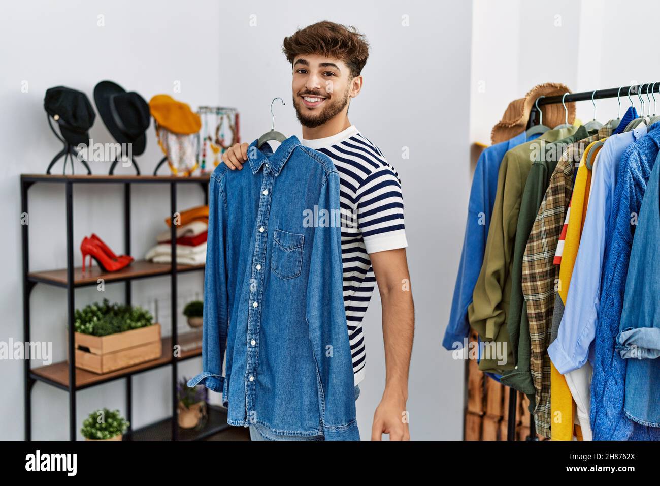 Young arab man customer holding shirt shopping at clothing store Stock ...