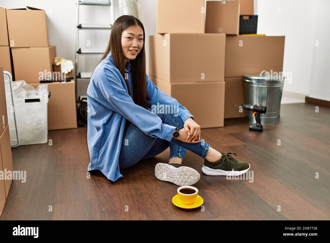Young chinese girl smiling happy sitting on the floor at new home Stock ...