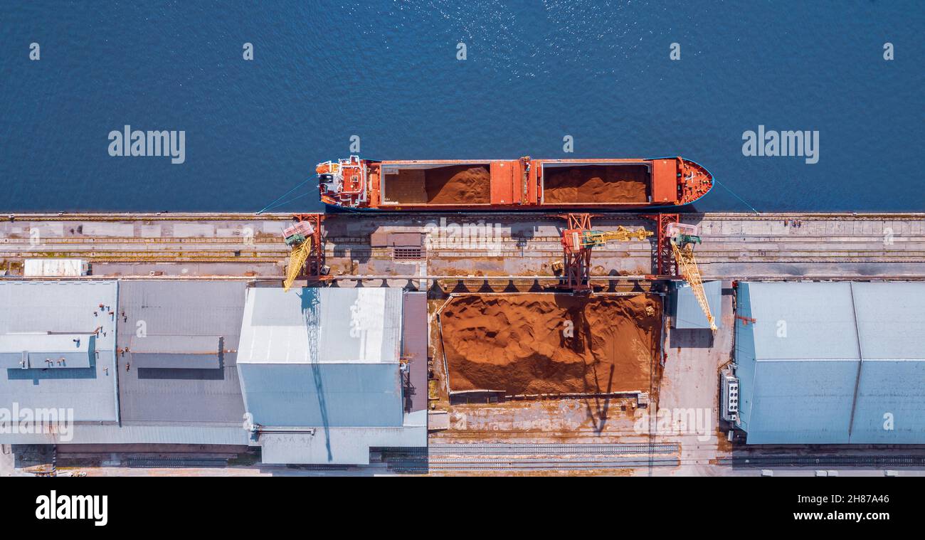 Loading sand onto ship in cargo port, building materials for hard to reach regions. Stock Photo