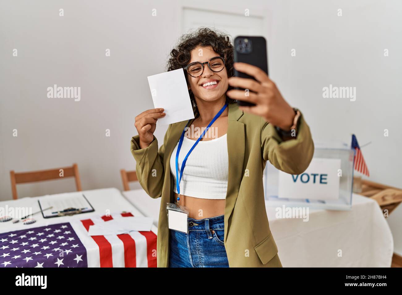 Young hispanic woman holding vote make selfie by the smartphone at electoral college Stock Photo