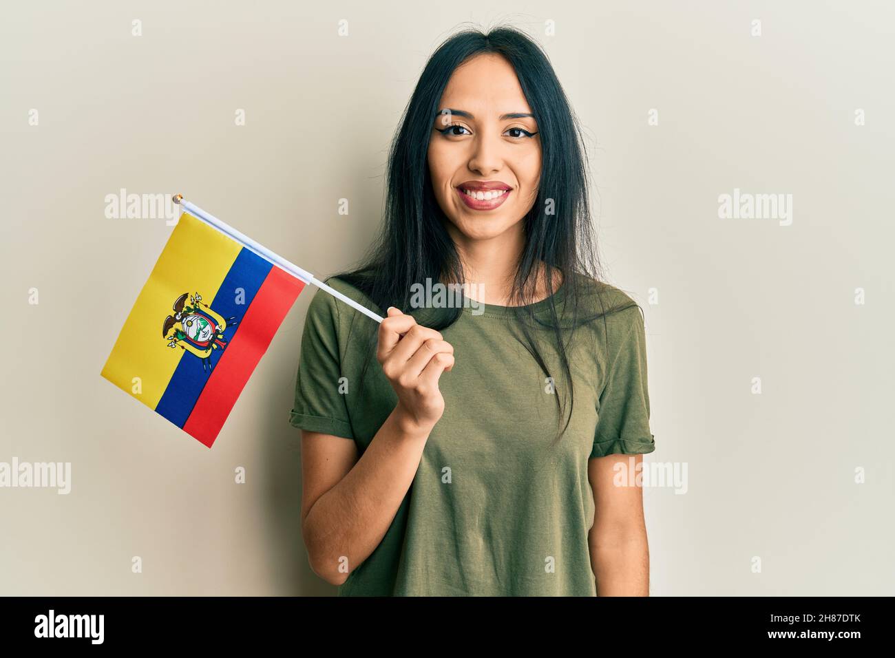 Young hispanic girl holding ecuador flag looking positive and happy standing and smiling with a confident smile showing teeth Stock Photo