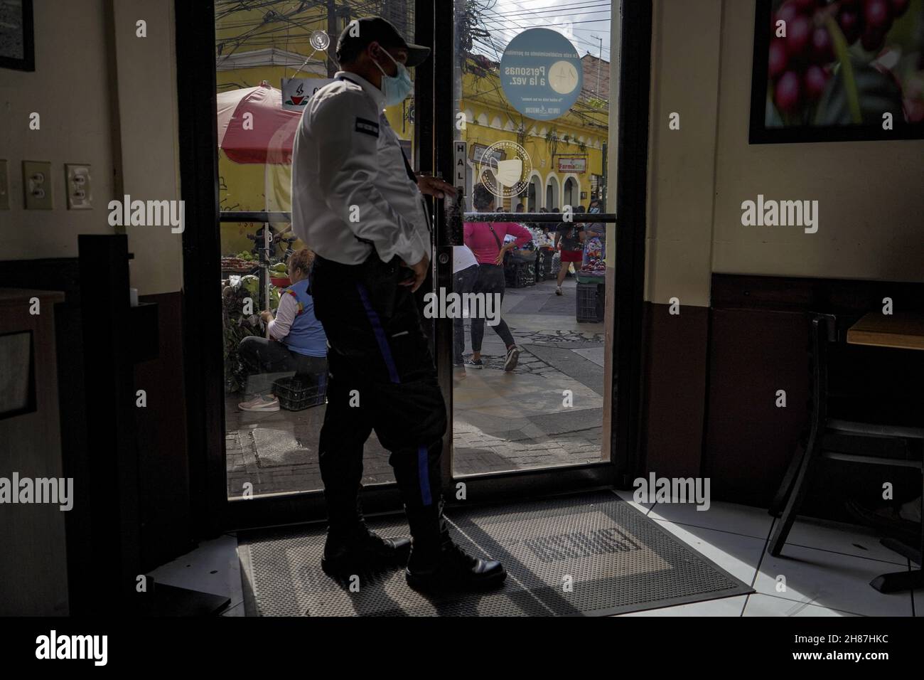 Tegucigalpa, Honduras. 27th Nov, 2021. A security guard checks on people as they walk by a local business amidst fears of looting after the announcement of the election results.The Republic of Honduras will hold general elections to choose a new set of president, congress, and municipal government leaders. (Photo by Camilo Freedman/SOPA Images/Sipa USA) Credit: Sipa USA/Alamy Live News Stock Photo