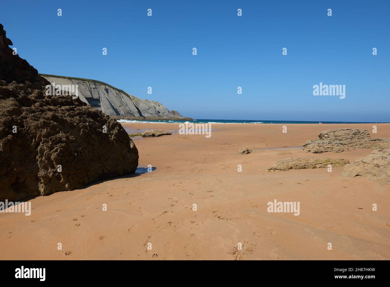 A quiet fine sandy beach with cliffs in the background Stock Photo