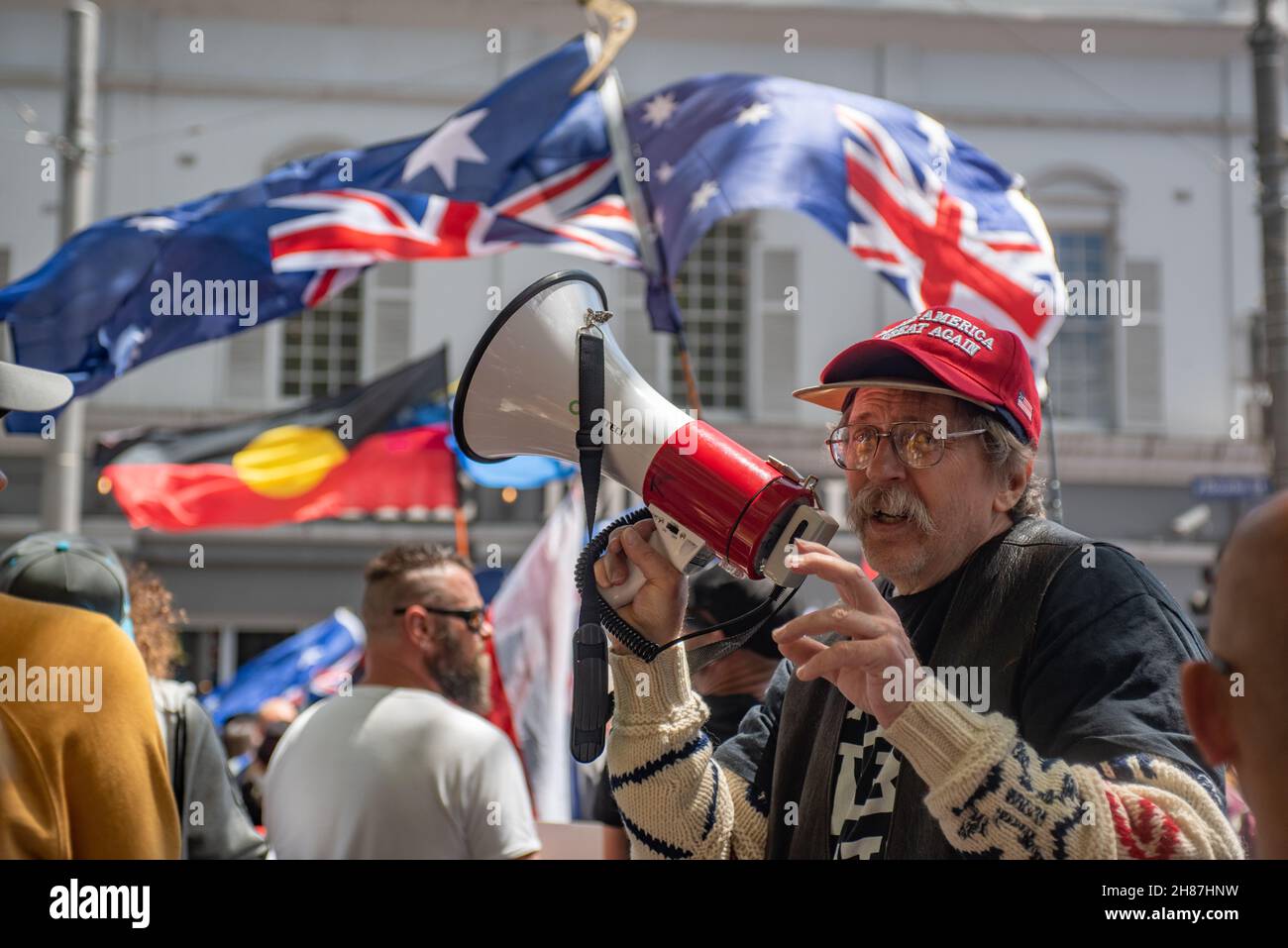 27th November 2021. Australian and Indigenous flags fly while a man with a MAGA hat speaks into a megaphone. Credit: Jay Kogler/Alamy Live News Stock Photo