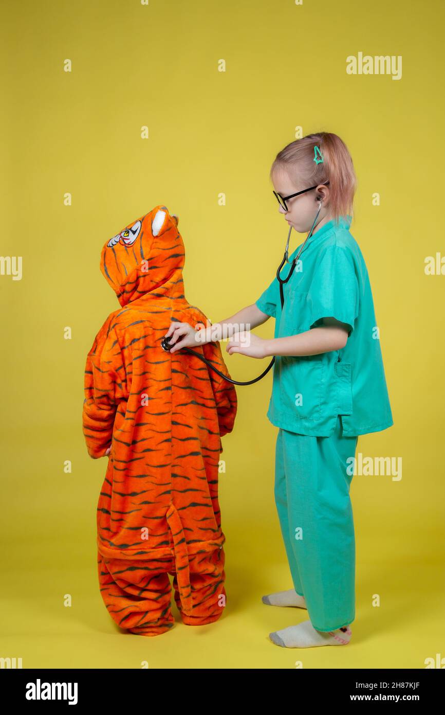 Little caucasian children play doctor, a boy in a tiger costume came to the pediatrician for an appointment Stock Photo