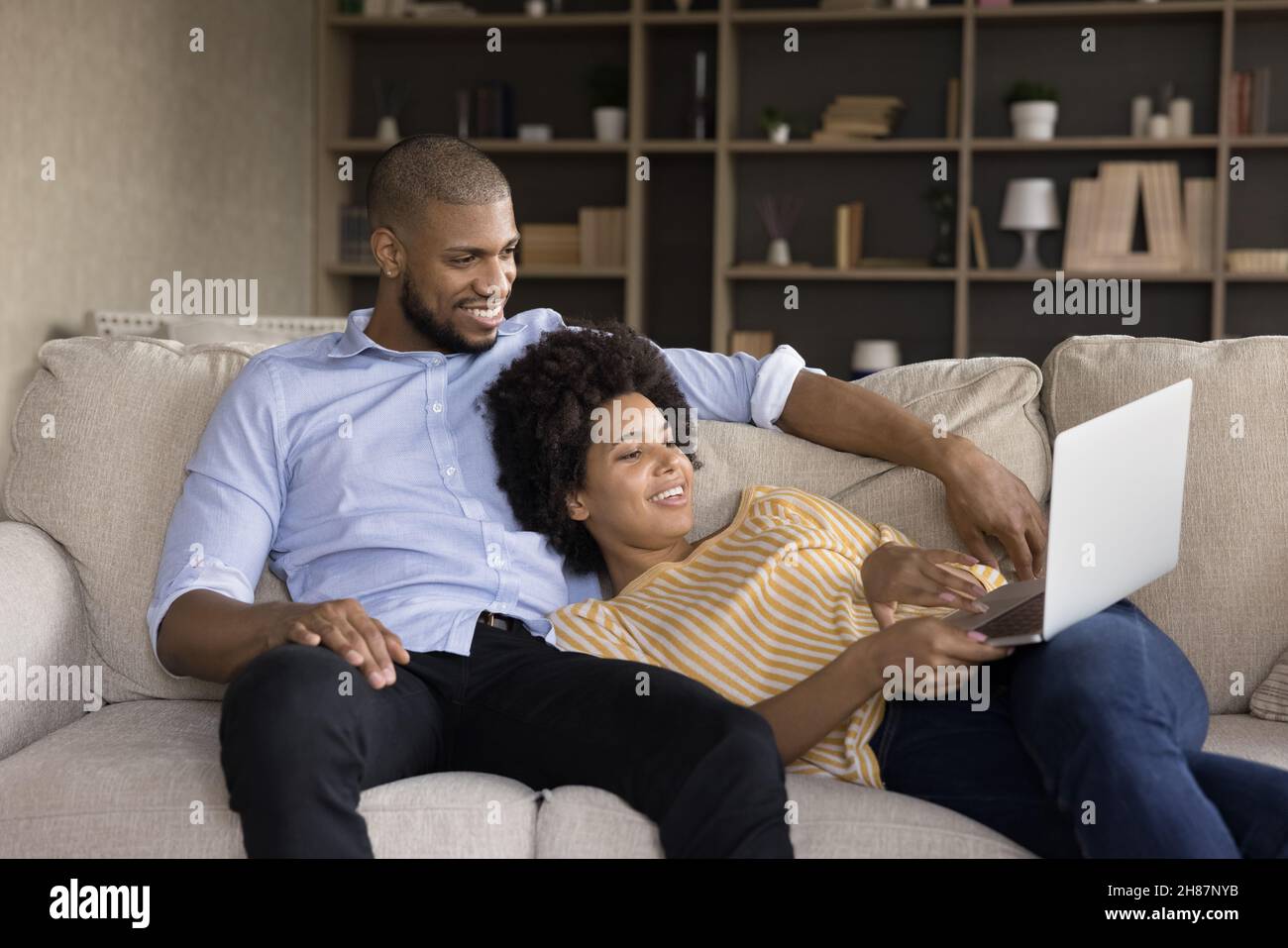 Happy relaxed Black married couple resting on sofa Stock Photo
