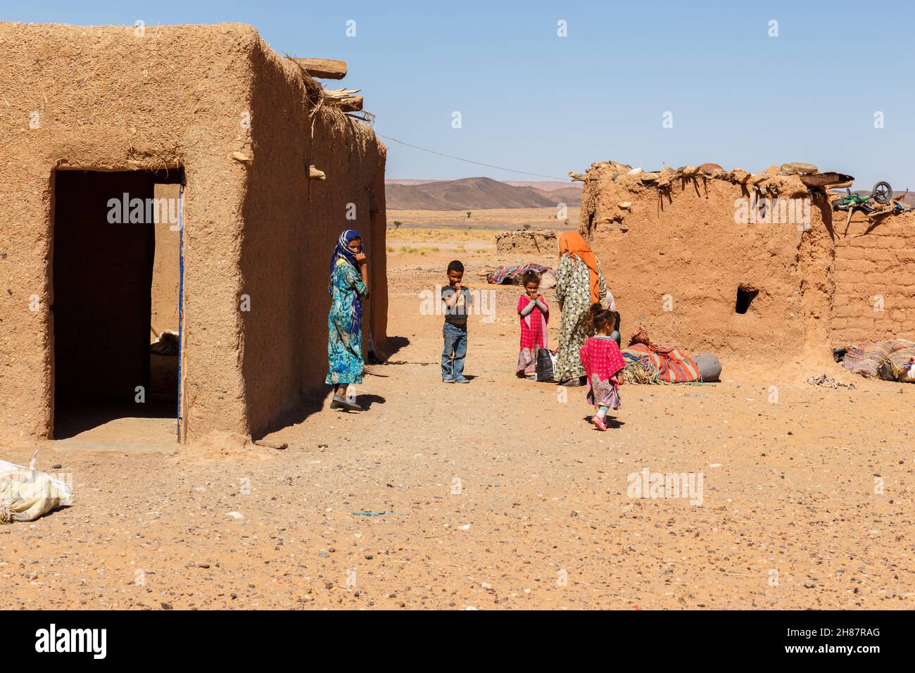Errachidia Province, Morocco - October 15, 2015: Berber huts in the Sahara Desert. Berber women and children stand outside the house. Stock Photo