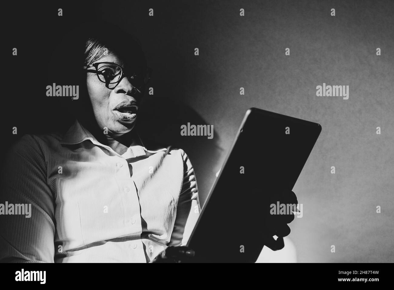 African-American woman looking at black and white tablet Stock Photo