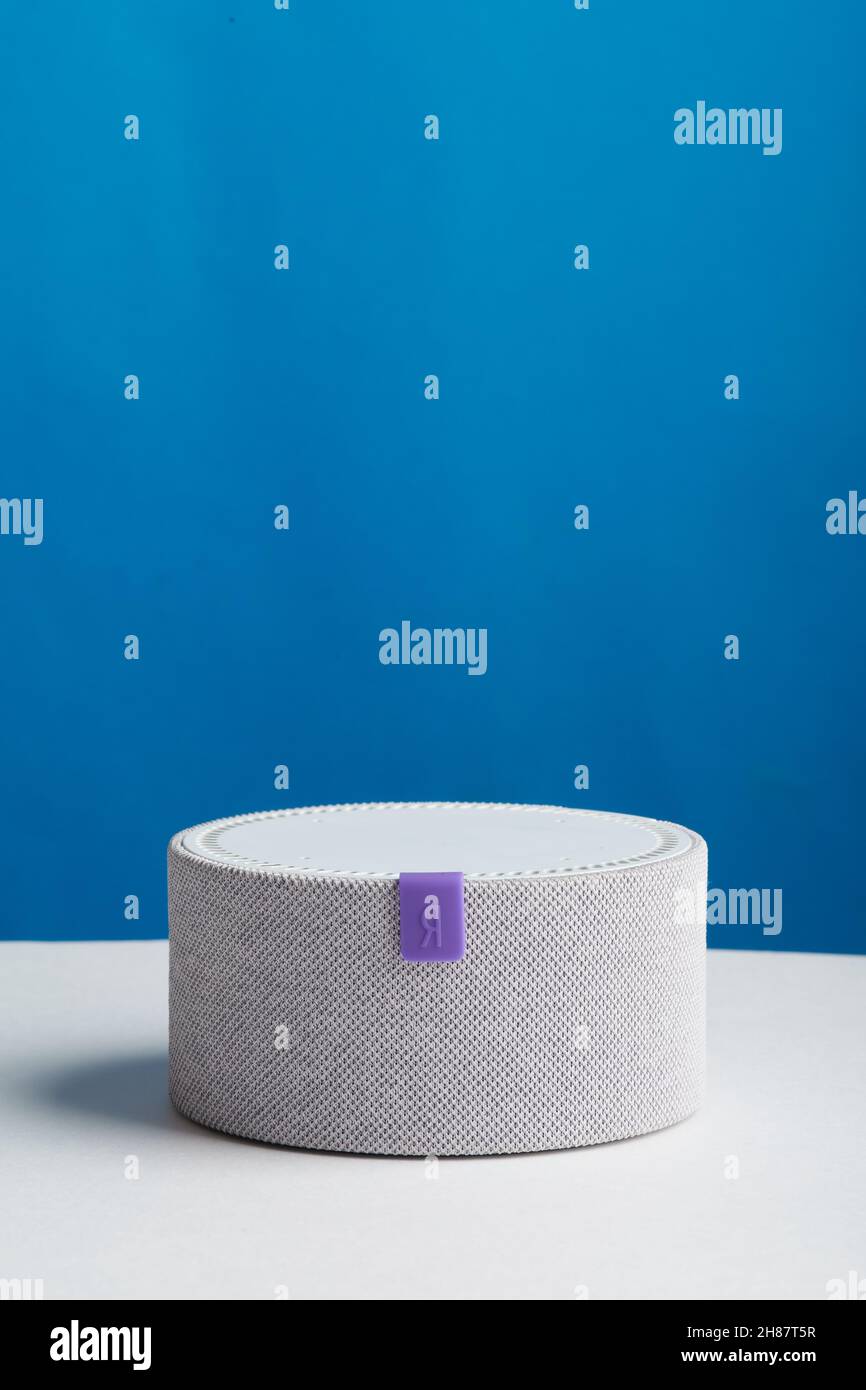 Smart speaker Yandex mini on white table and blue background Stock Photo