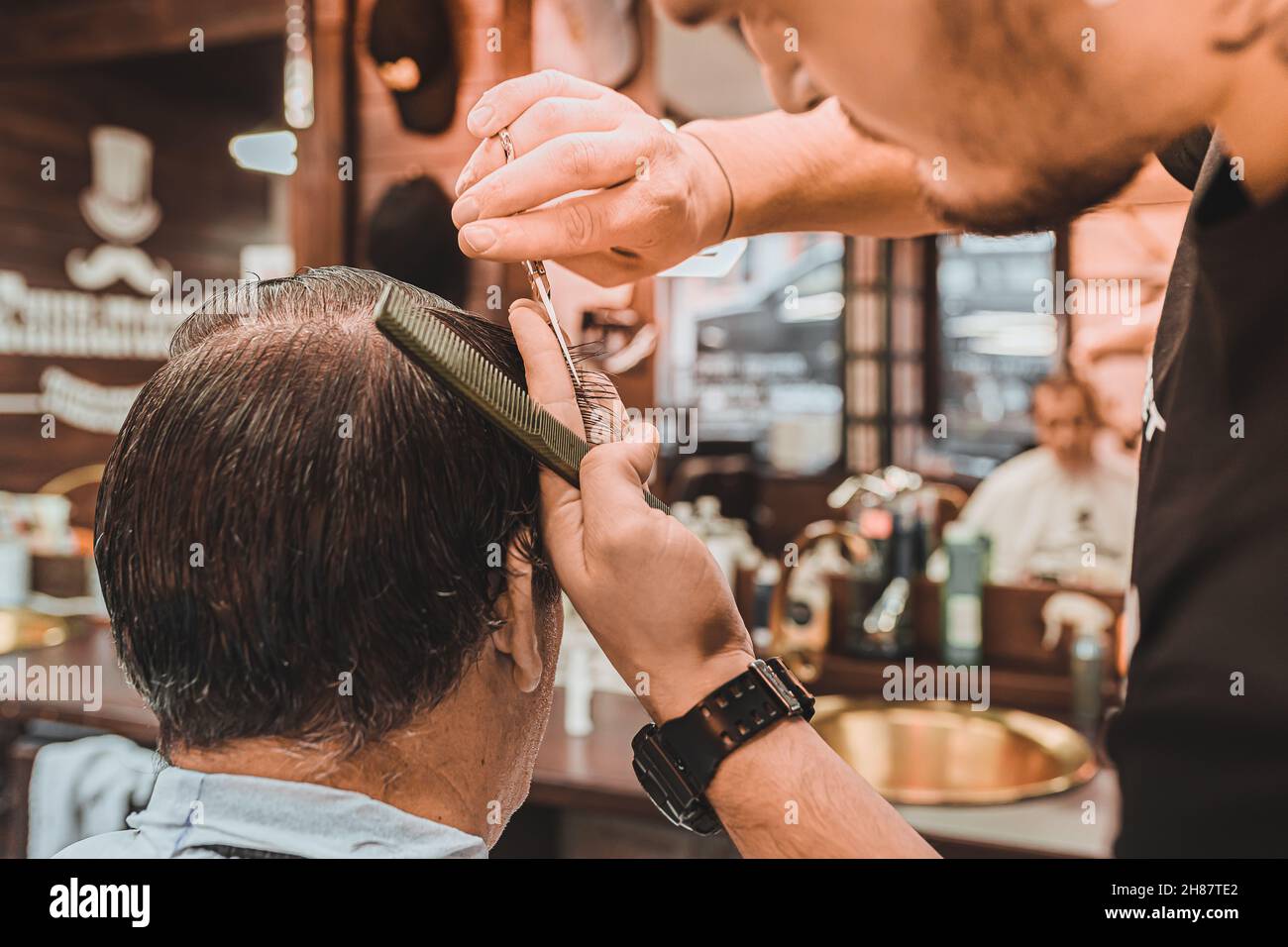 Barbershop. hairdresser professionally performs a haircut for men. man client sits in professional barber chair, and hairdresser makes haircut. Stock Photo