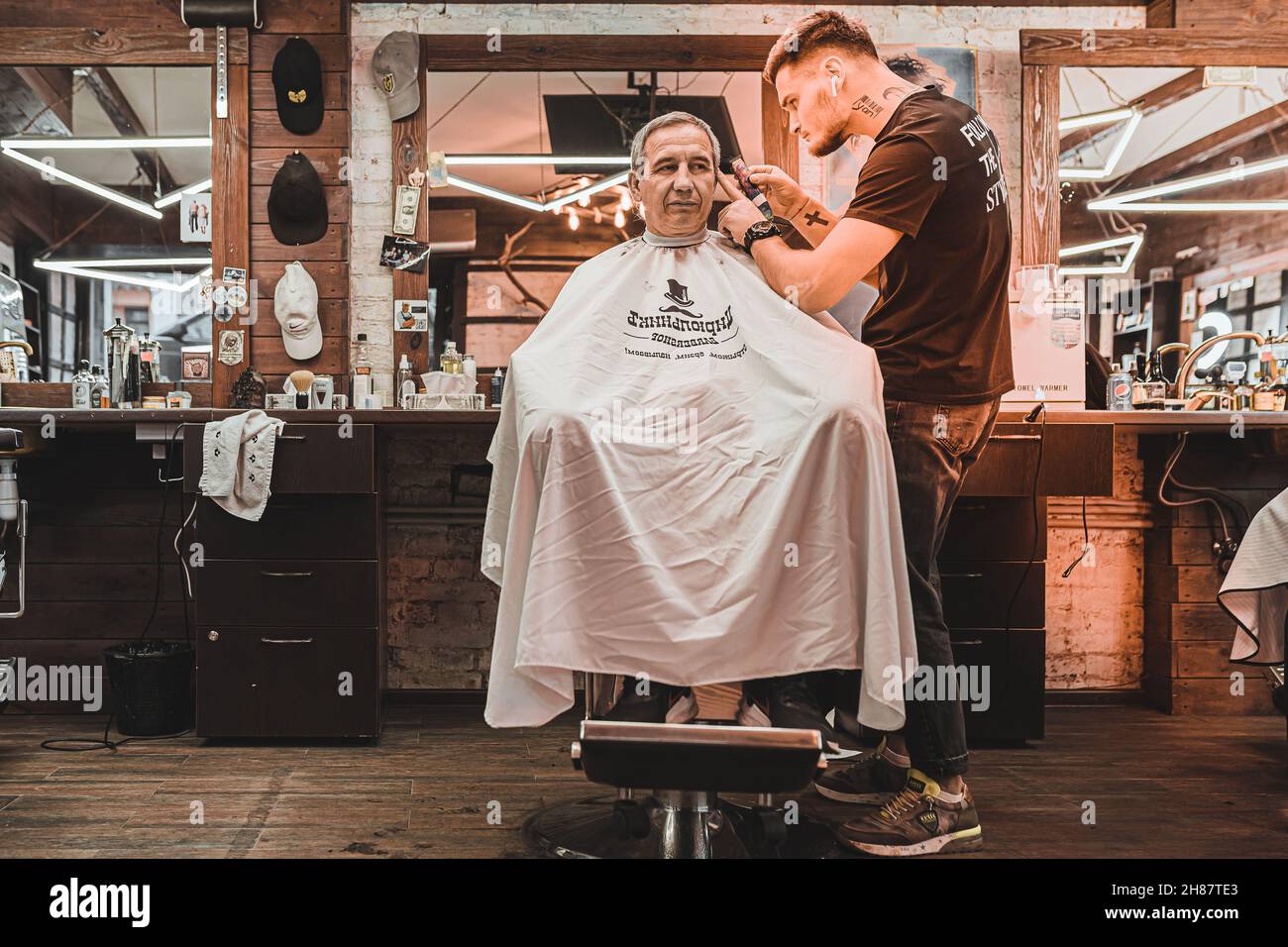 Barbershop. hairdresser professionally performs haircut for men. man client sits in professional barber chair, and hairdresser makes haircut. Stock Photo