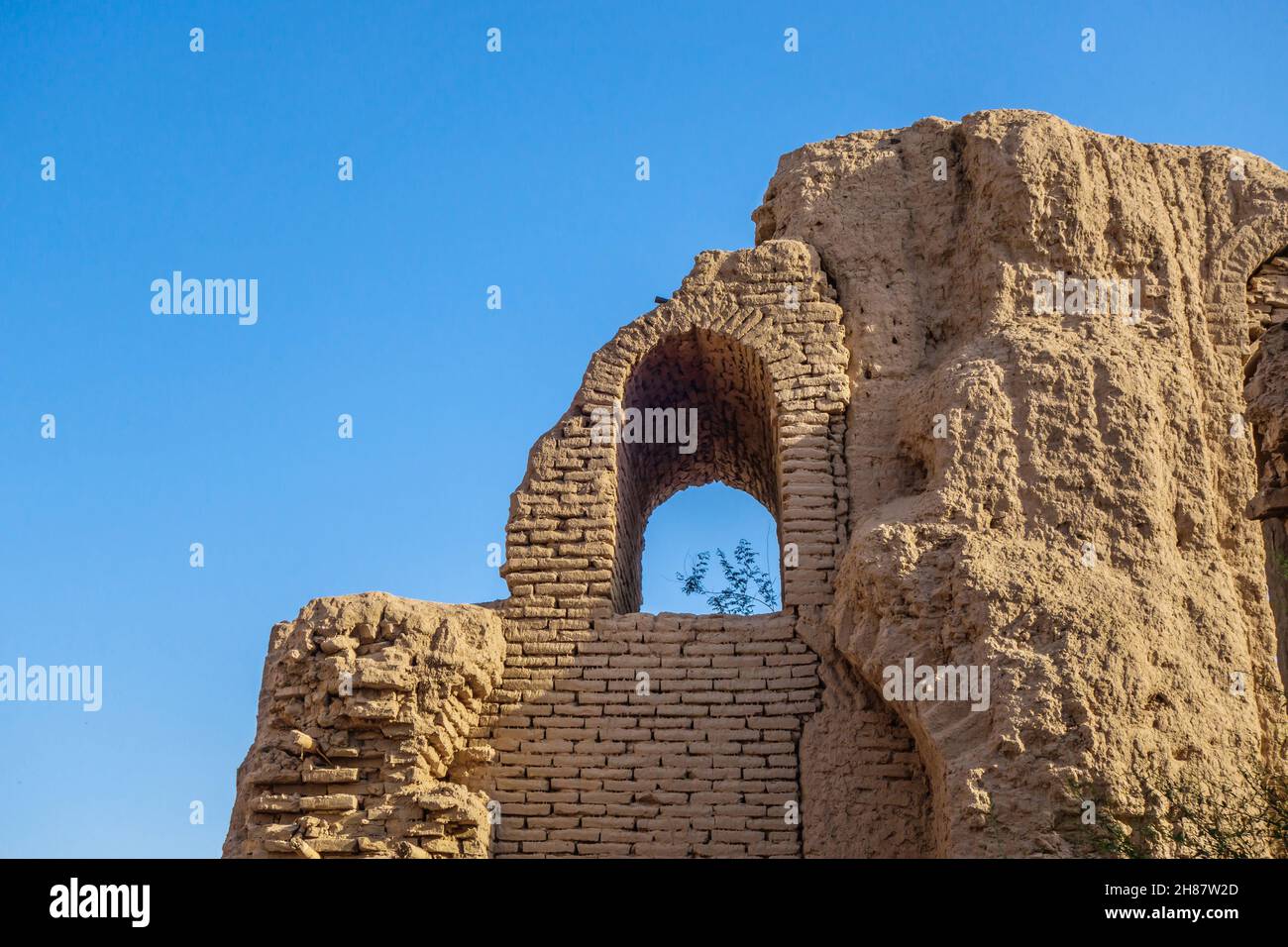 Part of a collapsed wall and a window opening overlooking the clear blue sky. Medieval architectural monument of the 9th century - the palace or carav Stock Photo