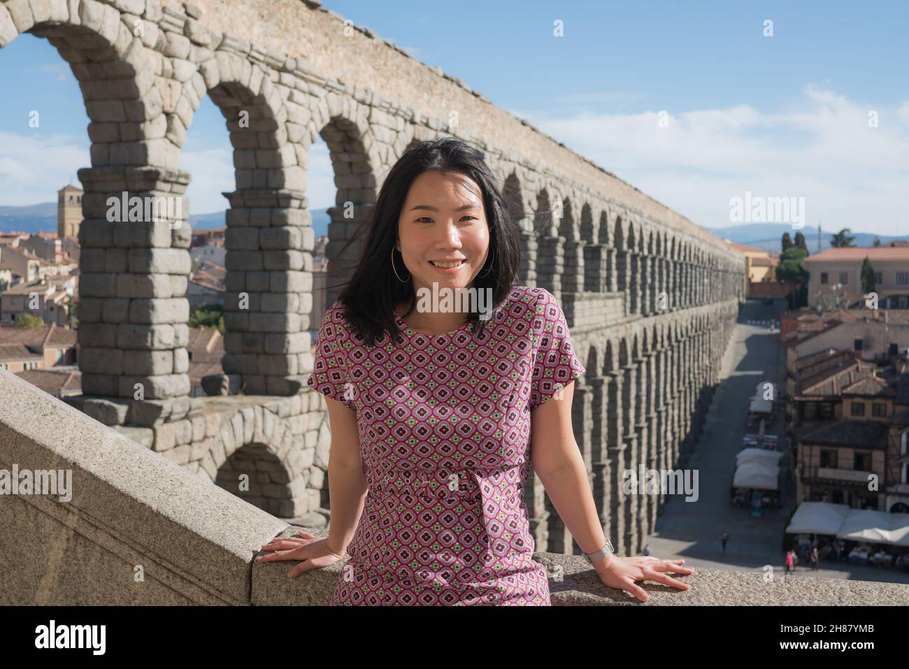 Attractive Asian girl during vacation in Spain - young happy and beautiful Chinese woman visiting world heritage aqueduct in Segovia enjoying holidays Stock Photo