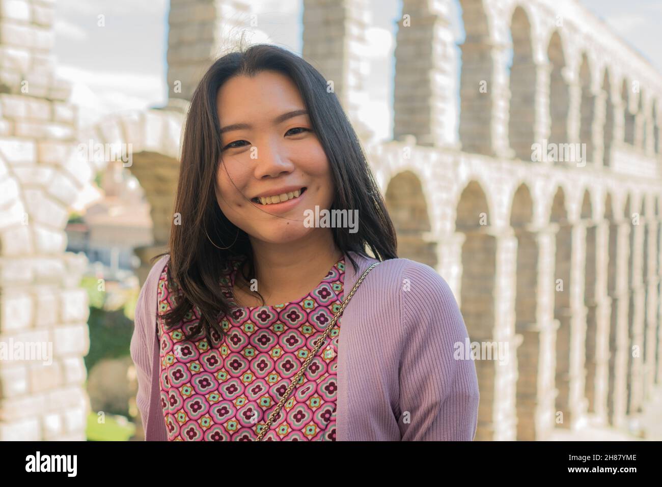 Attractive Asian girl during vacation in Spain - young happy and beautiful Chinese woman visiting world heritage aqueduct in Segovia enjoying holidays Stock Photo