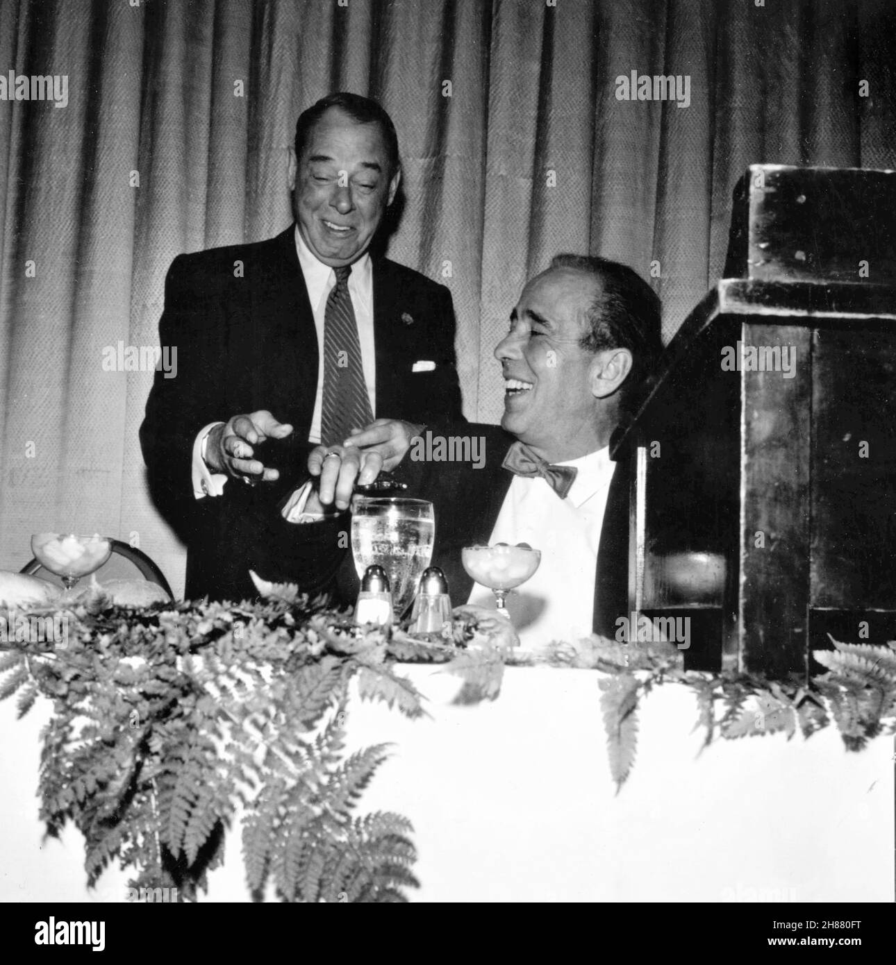 HUMPHREY BOGART candid photo with comedian JOE E. LEWIS during his afternoon NEW YORK FRIARS CLUB ROAST in September 1955 Stock Photo