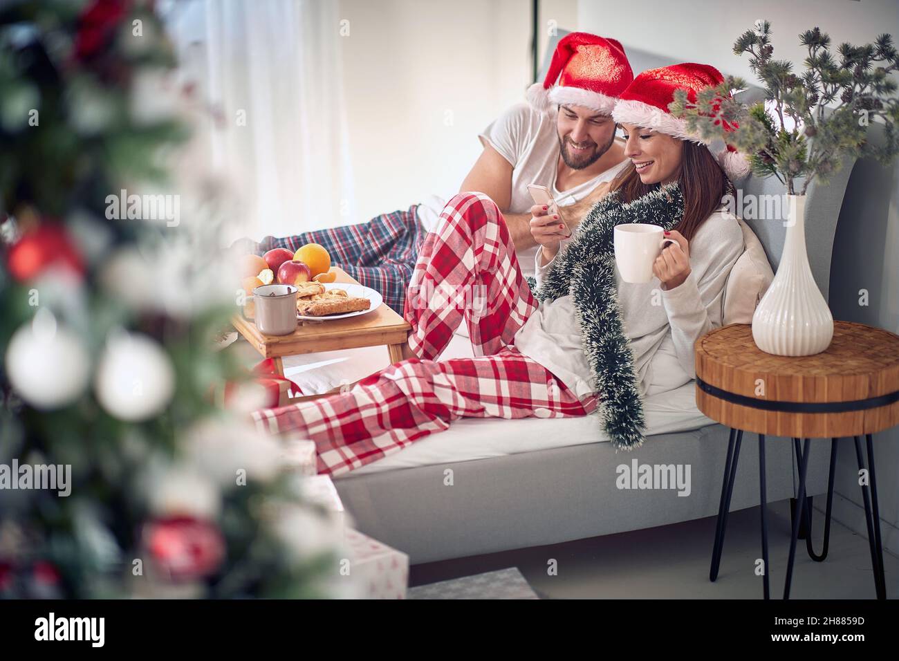Happy Christmas morning in the bed.Men and smiling woman at Christmas morning texing mesage Stock Photo