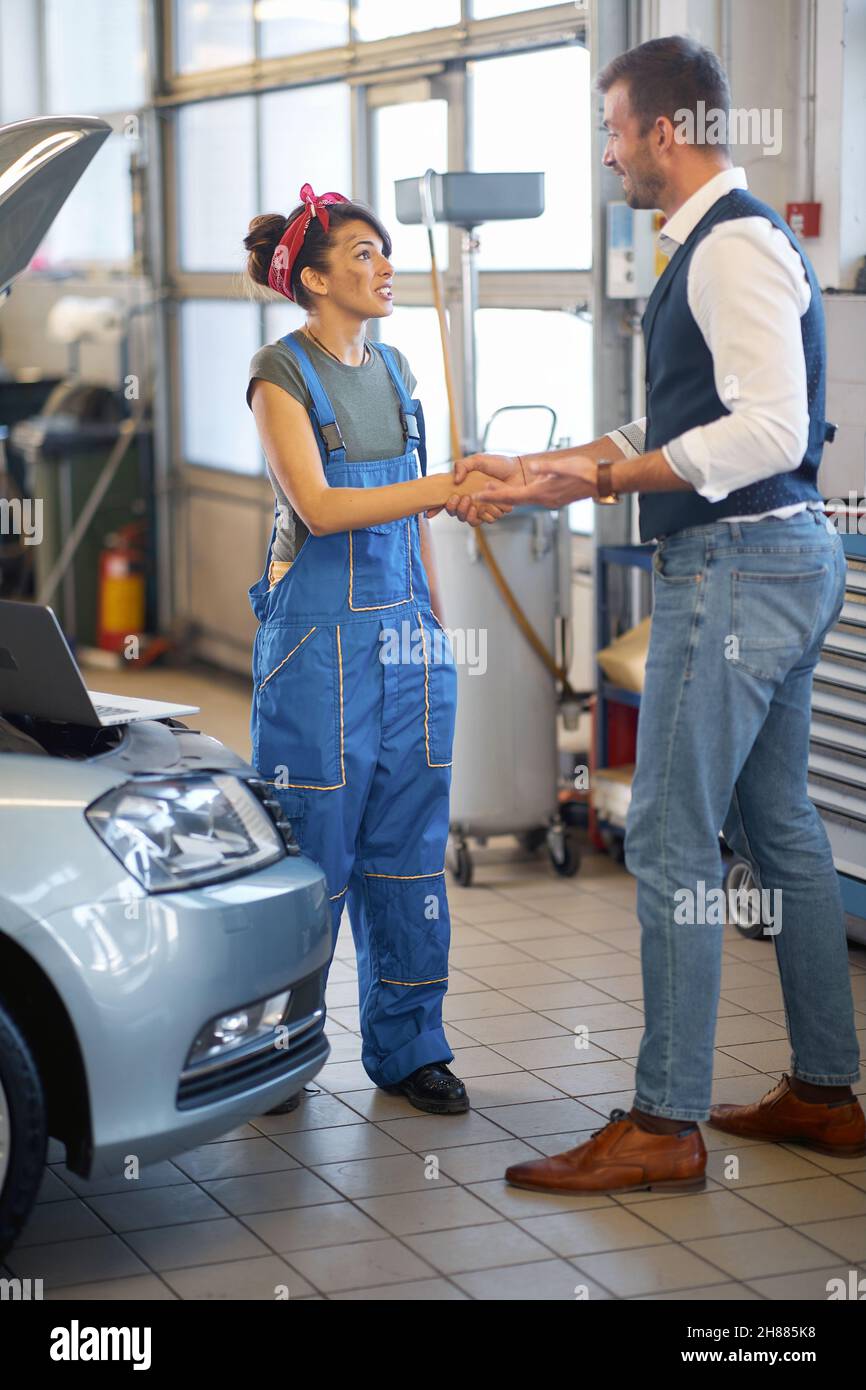 The car was repaired. Satisfied client and smiling female mechanic Stock Photo