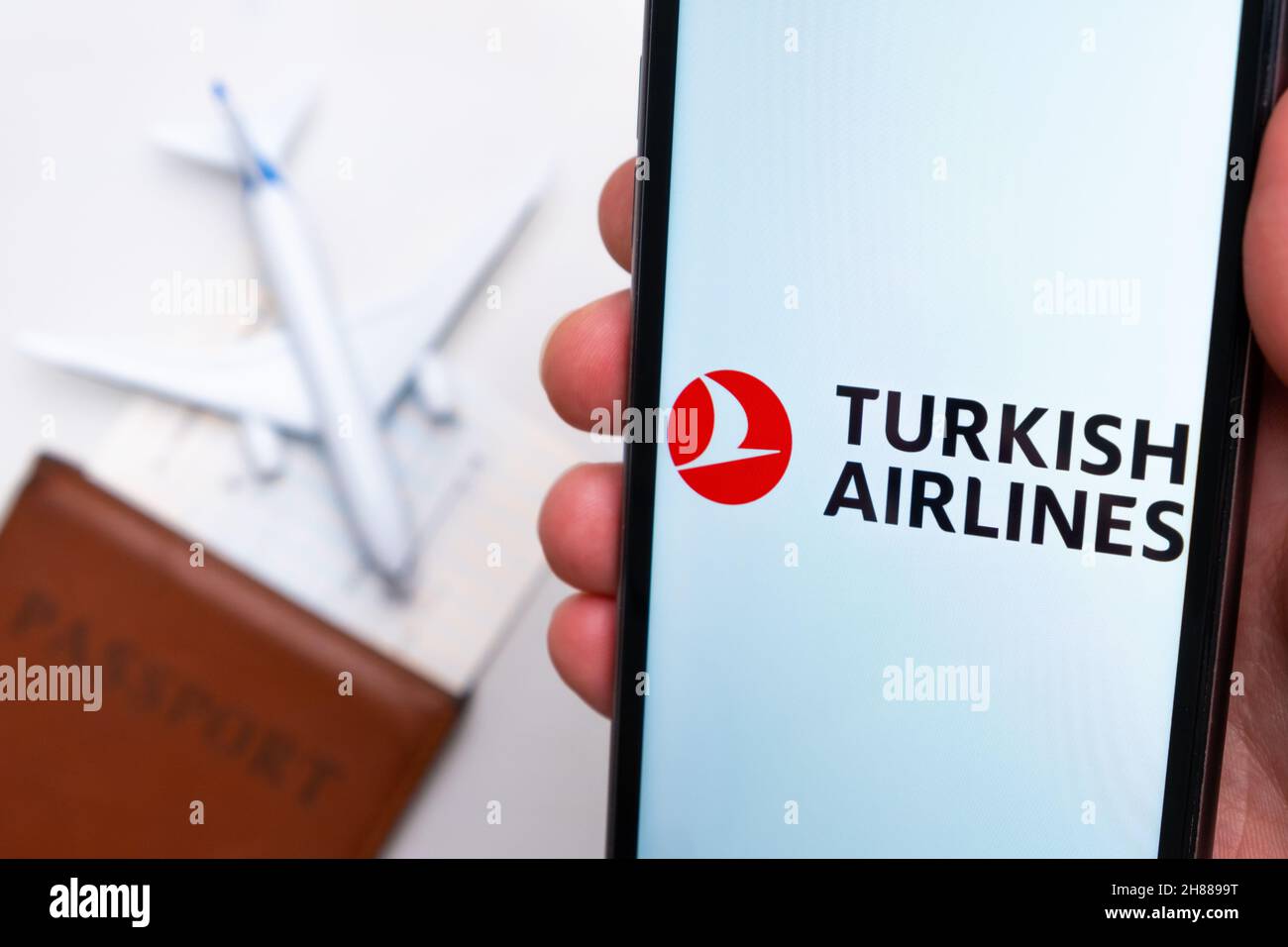 Turkish Airlines app on a smartphone screen with a plane and passport on the background. The concept of travel app. November 2021, San Francisco, USA Stock Photo