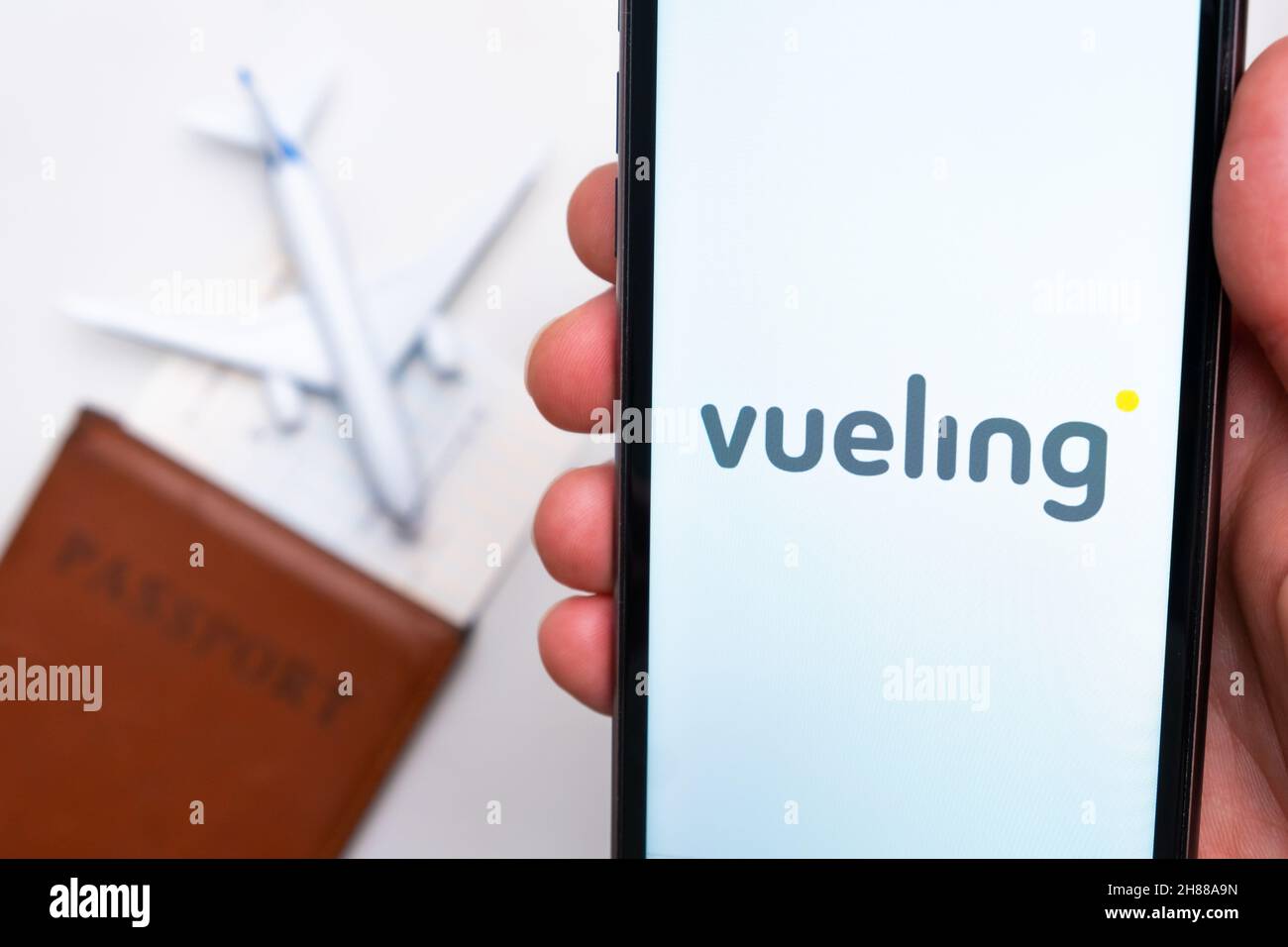 Vueling Airline app on a smartphone screen with a plane and passport on the background. The concept of travel app. November 2021, San Francisco, USA Stock Photo