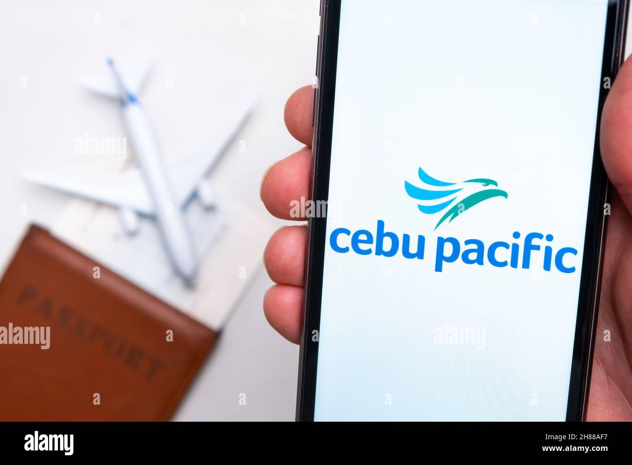 Cebu pacific Airlines app logo on the screen of mobile phone. A blurry image of a plane, a passport and boarding pass on the background. November 2021, San Francisco, USA Stock Photo