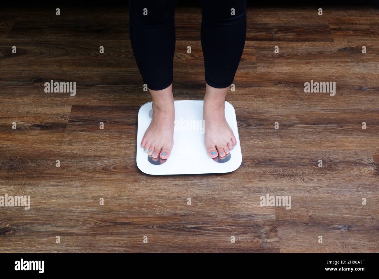 Closeup female feet stepping on body weight scale. Weight control
