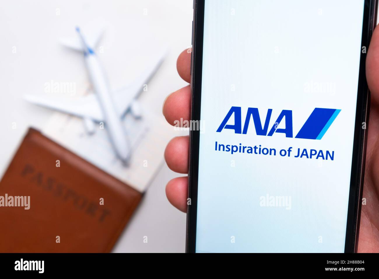 ANA Inspiration of Japan Airline app on a smartphone screen with a plane and passport on the background. The concept of travel app. November 2021, San Francisco, USA Stock Photo
