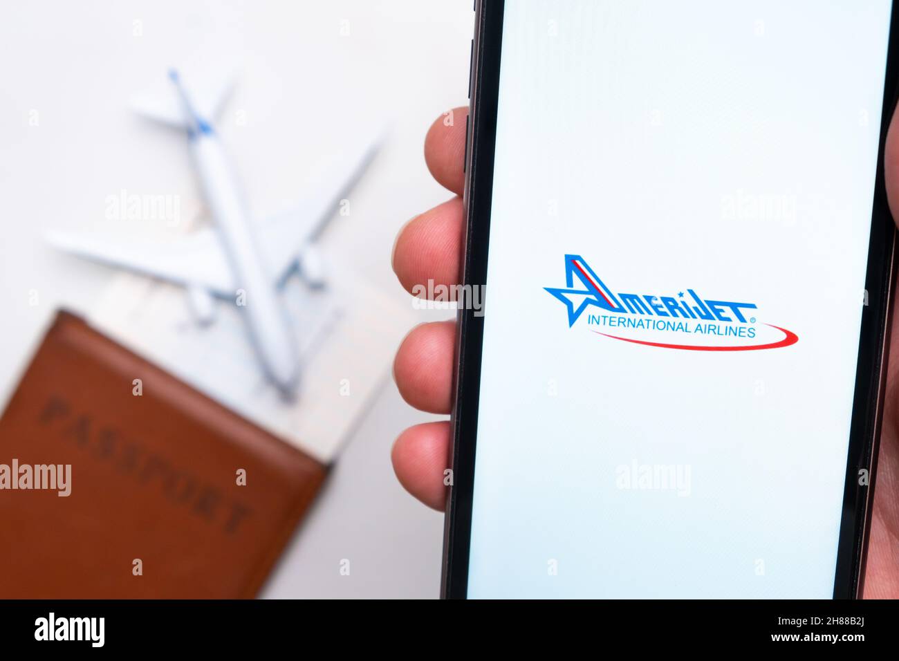 AmeriJet International Airline app on a smartphone screen with a plane and passport on the background. The concept of travel app. November 2021, San Francisco, USA Stock Photo