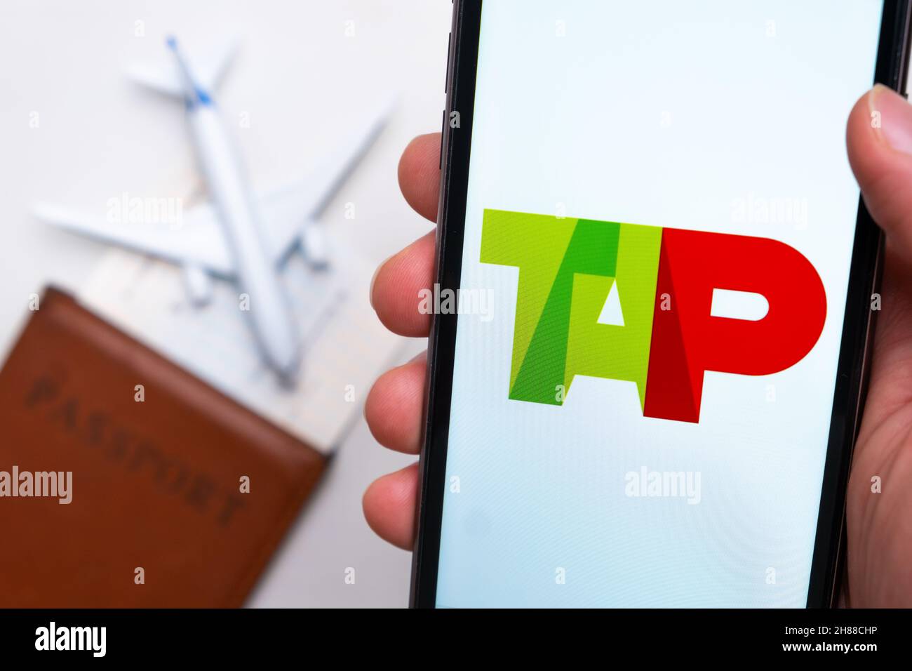 TAP Airlines app on the cell phone screen in mans hand with plane, boarding  pass and passport on the background. The concept of the airlines mobile  application. November 2021, San Francisco, USA