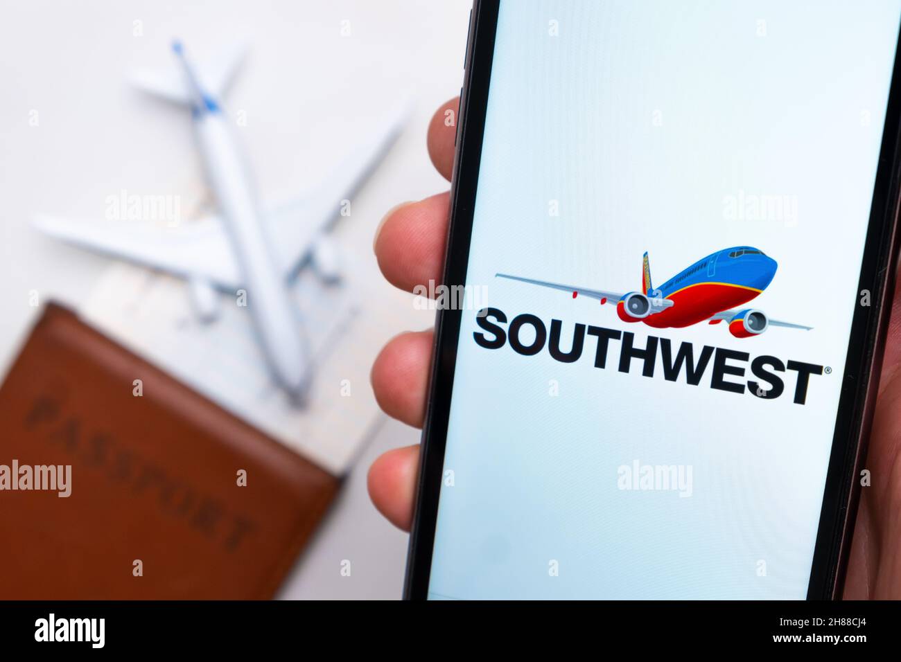 Southwest Airlines app on the cell phone screen in mans hand with plane, boarding pass and passport on the background. The concept of the airlines mobile application. November 2021, San Francisco, USA Stock Photo