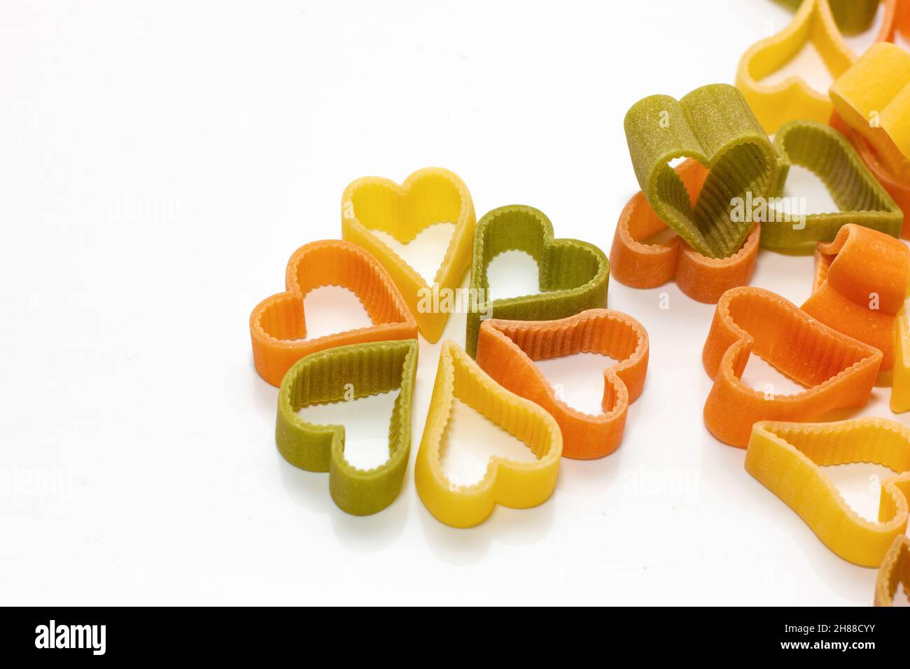 red, white, green pasta in the shape of a heart on a white background. Food concept. Stock Photo