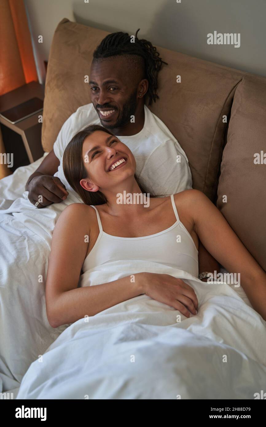 Happy lady and cheerful guy resting in bed Stock Photo