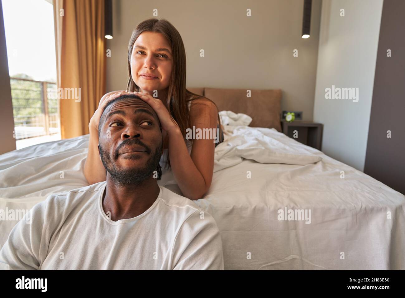 Joyous woman posing for camera with man in bedroom Stock Photo