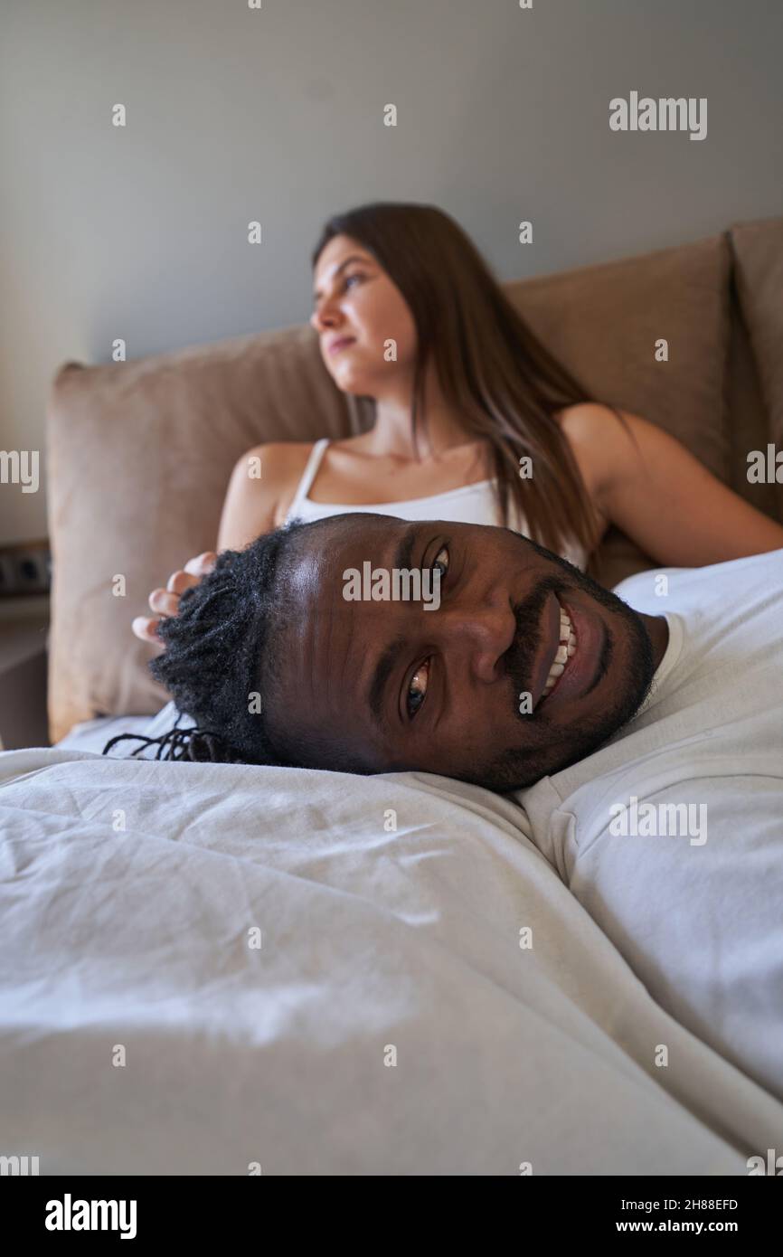 Joyous guy posing for camera with pensive lady on background Stock Photo