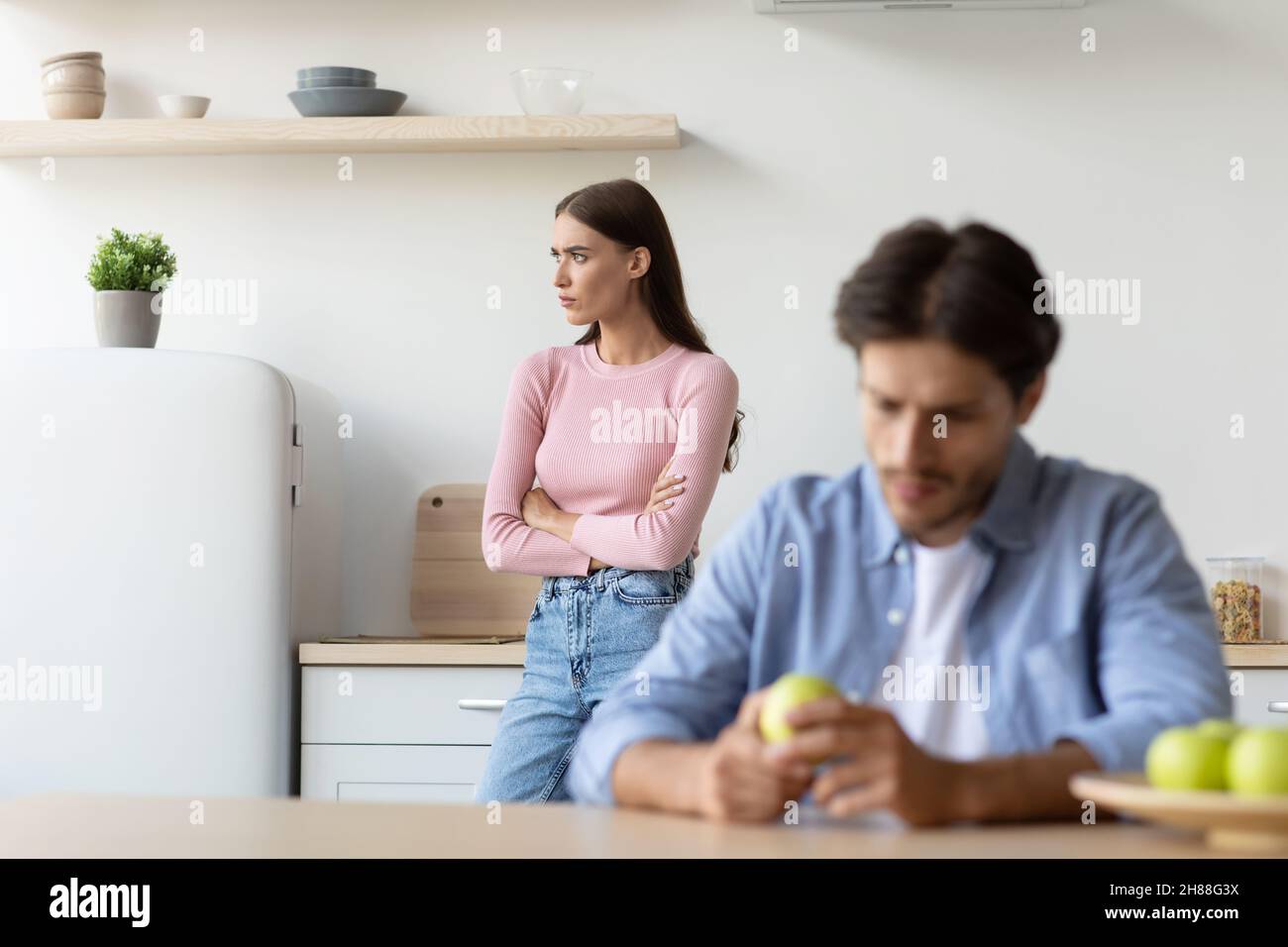 Offended sad young caucasian wife ignoring husband in minimalist kitchen interior Stock Photo