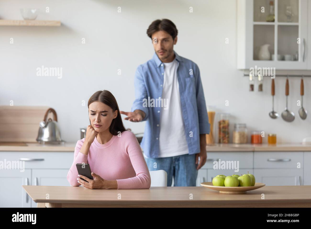 Unhappy millennial caucasian husband swears wife in minimalist kitchen interior Stock Photo