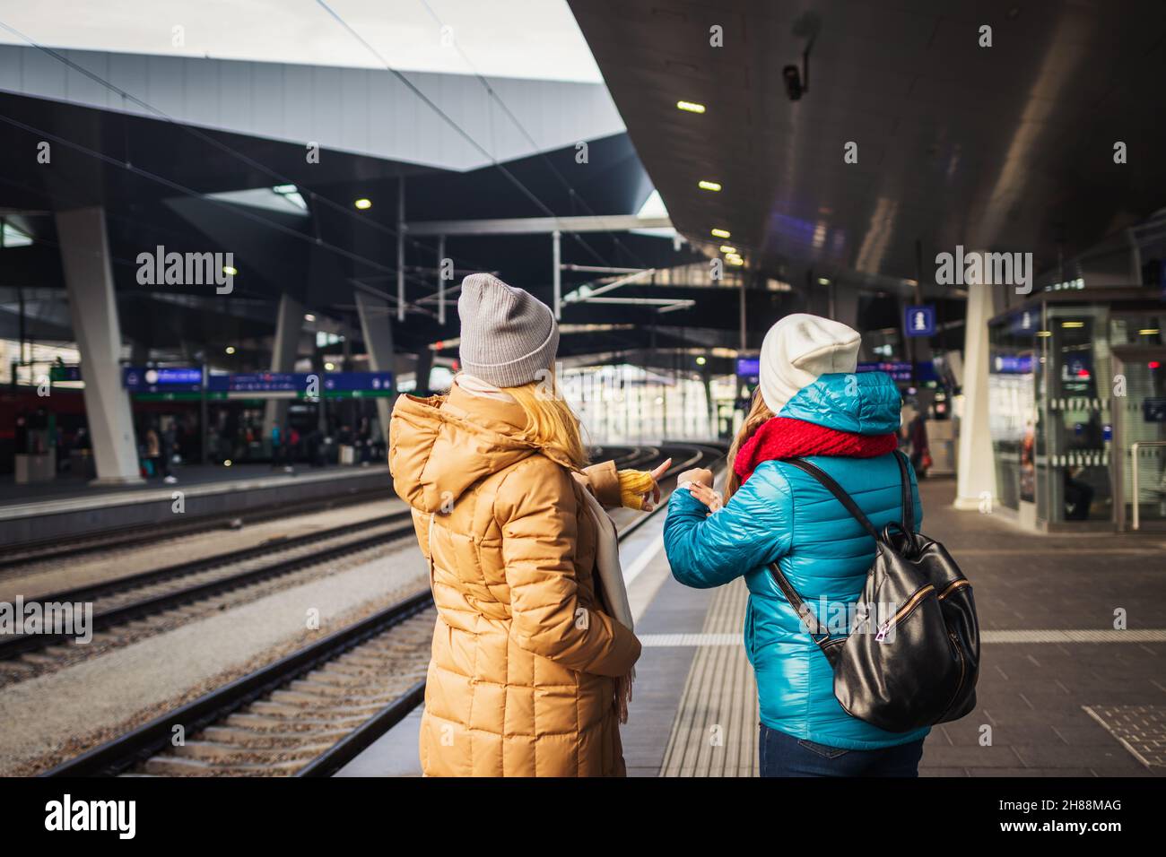Two women waiting for train at railway station and checking time. Delay train. Transportation and travel concept Stock Photo