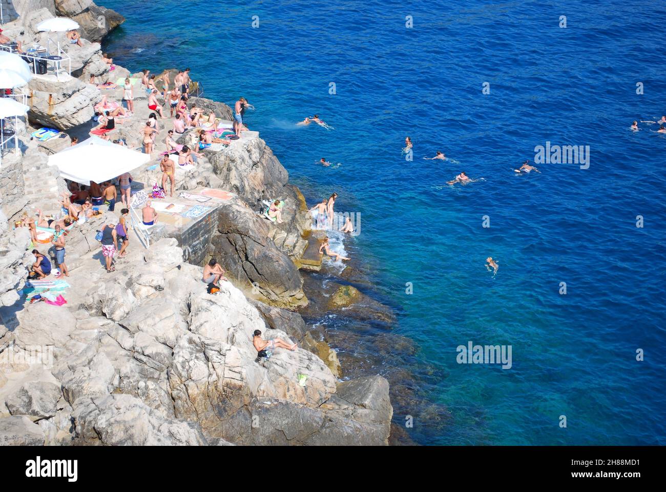Popular beach bar on the cliffs. Clients sunbathing and swimming