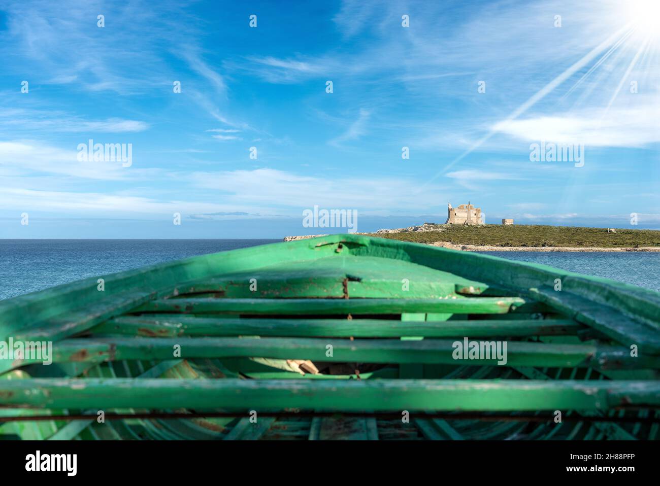 Green wooden boat of migrants and Mediterranean Sea in Portopalo di Capo Passero, Sicily island, Syracuse, Italy, south Europe Stock Photo
