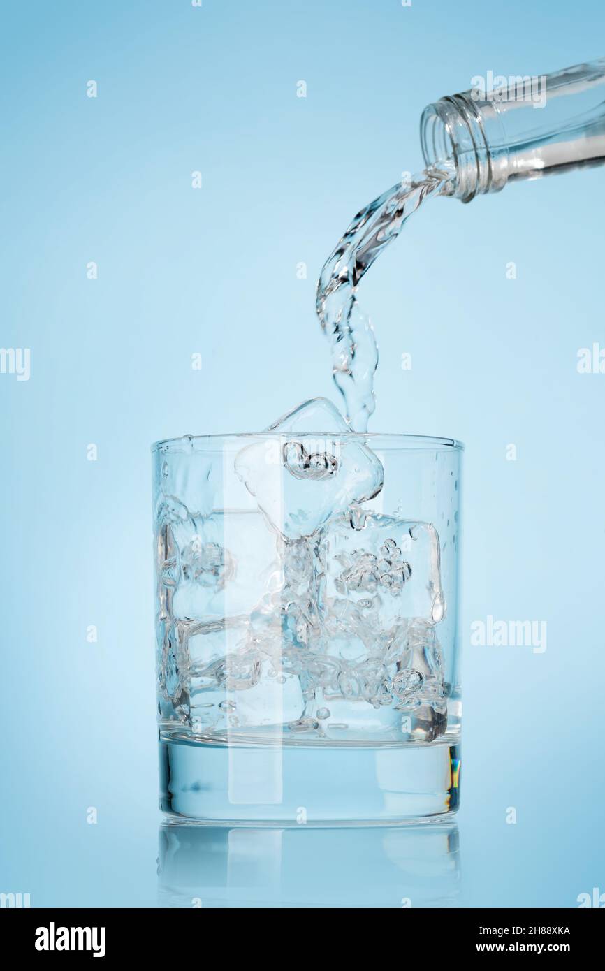 Glass with water and ice cubes over blue background Stock Photo - Alamy