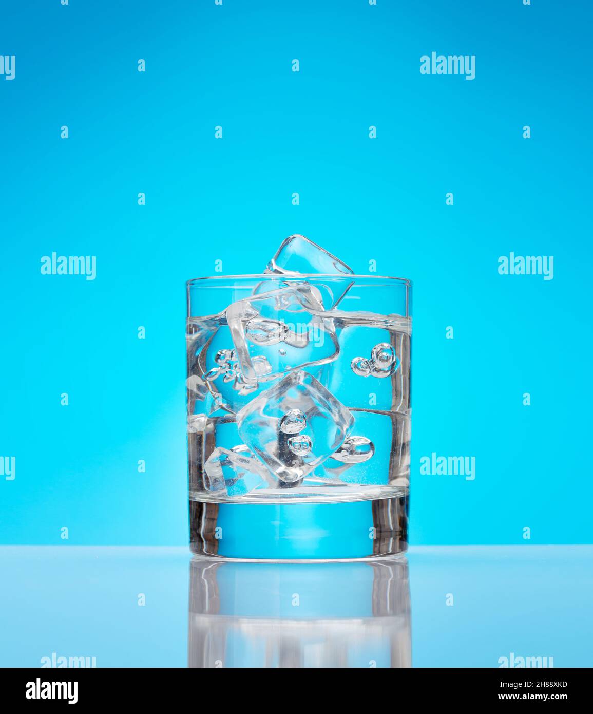 Glass with water and ice cubes over blue background Stock Photo - Alamy
