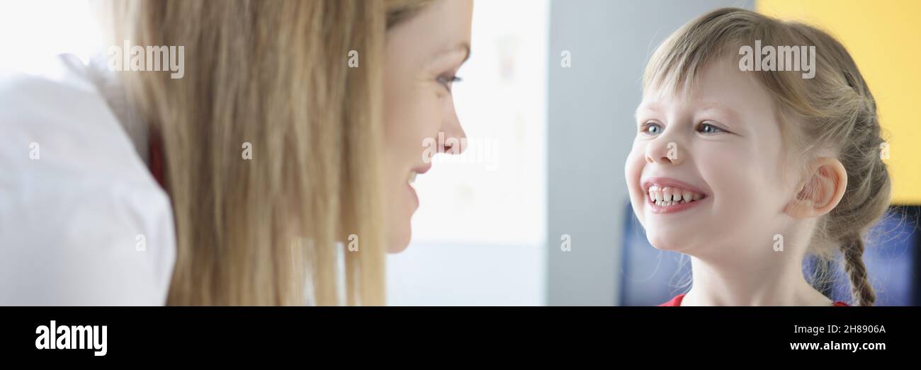 Woman speech therapist is engaged in speech with little girl Stock Photo
