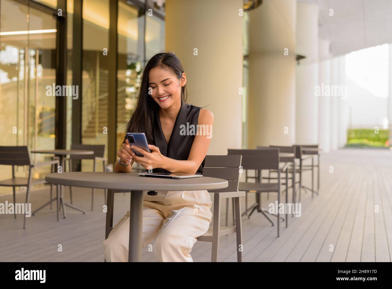 Portrait of beautiful Asian woman sitting outdoors at coffee shop restaurant during summer Stock Photo