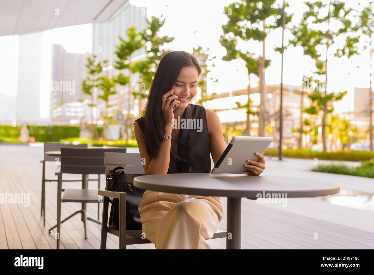 Portrait of beautiful Asian woman sitting outdoors at coffee shop restaurant during summer Stock Photo
