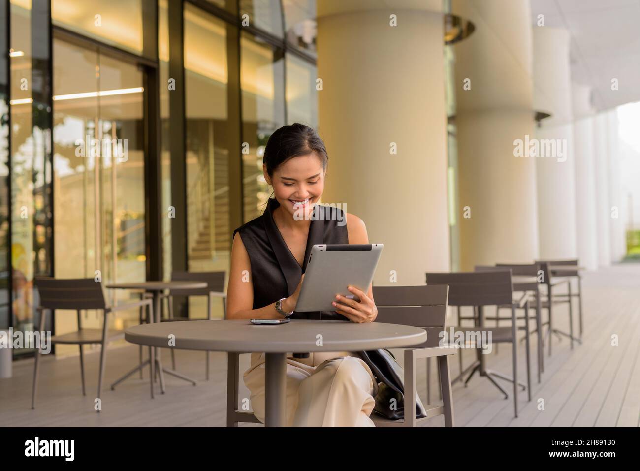 Portrait of beautiful Asian woman sitting outdoors at coffee shop restaurant during summer Stock Photo