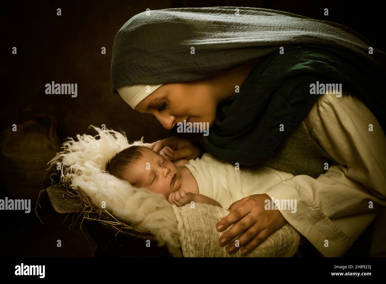 Living Christmas Nativity Scene of parents dressed in authentic clothes, with their 9 days old baby boy in swaddles Stock Photo