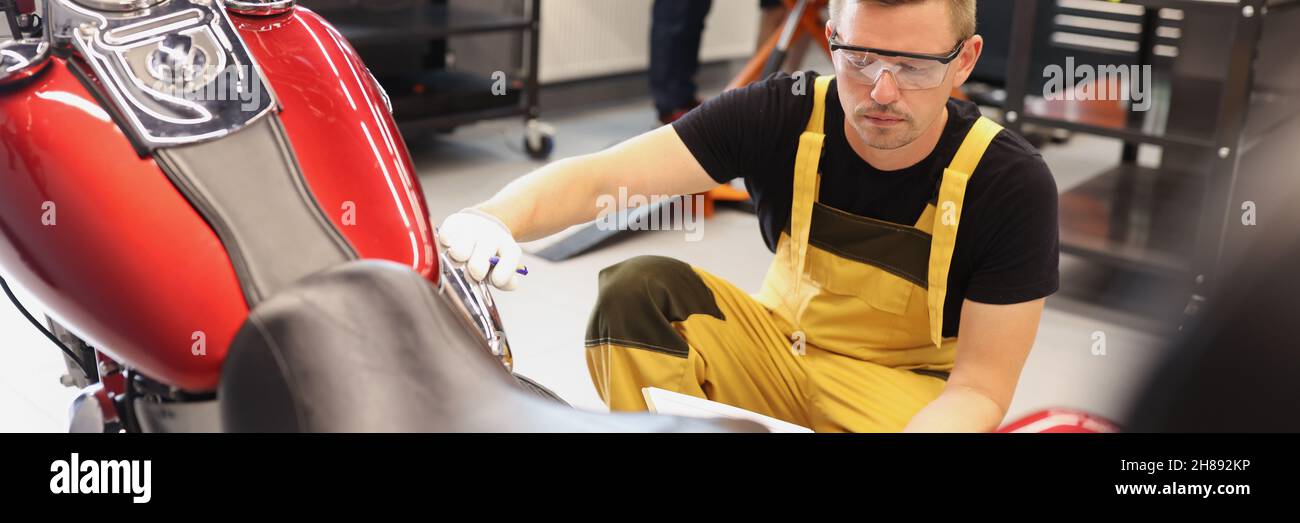 Auto mechanic checks technical condition of motorcycle in workshop Stock Photo