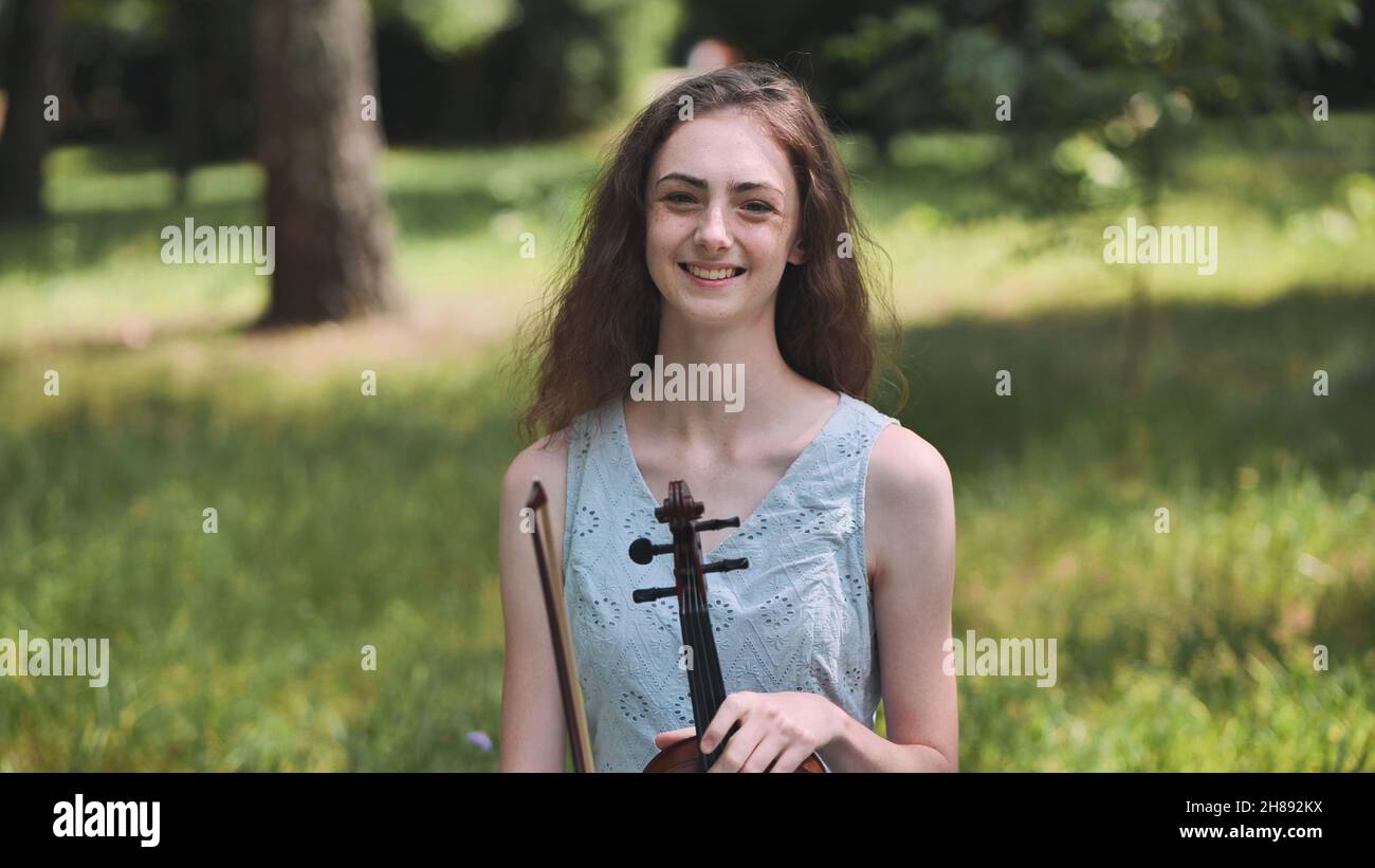 A young girl plays the violin in a city park Stock Photo - Alamy