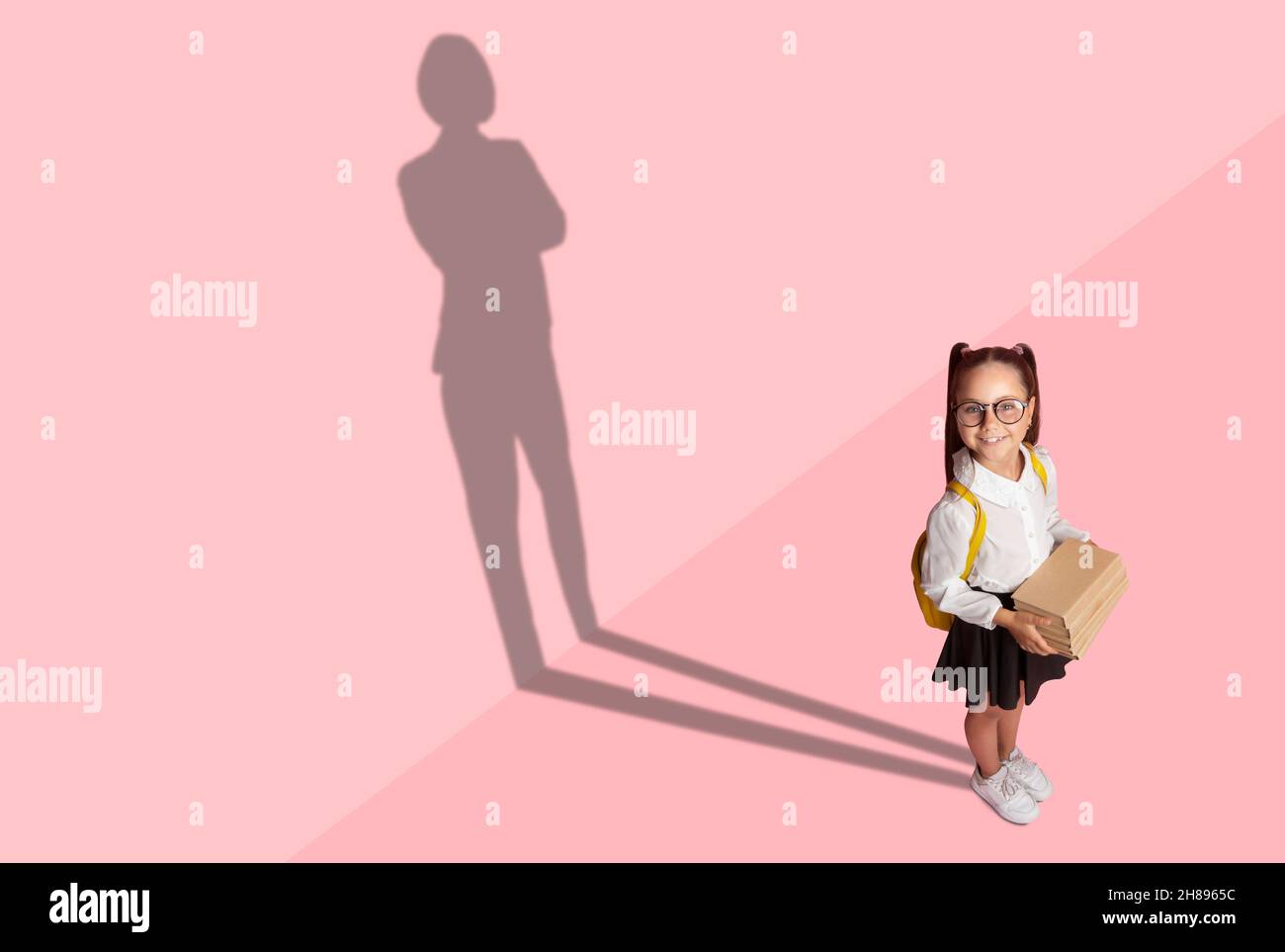 Cheerful little child in school uniform with businesswoman shadow Stock Photo